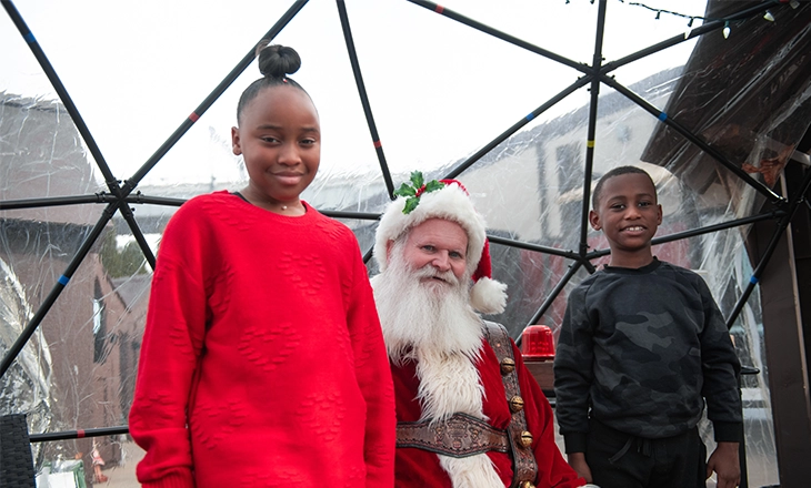 Photo of two children posing with Santa Claus