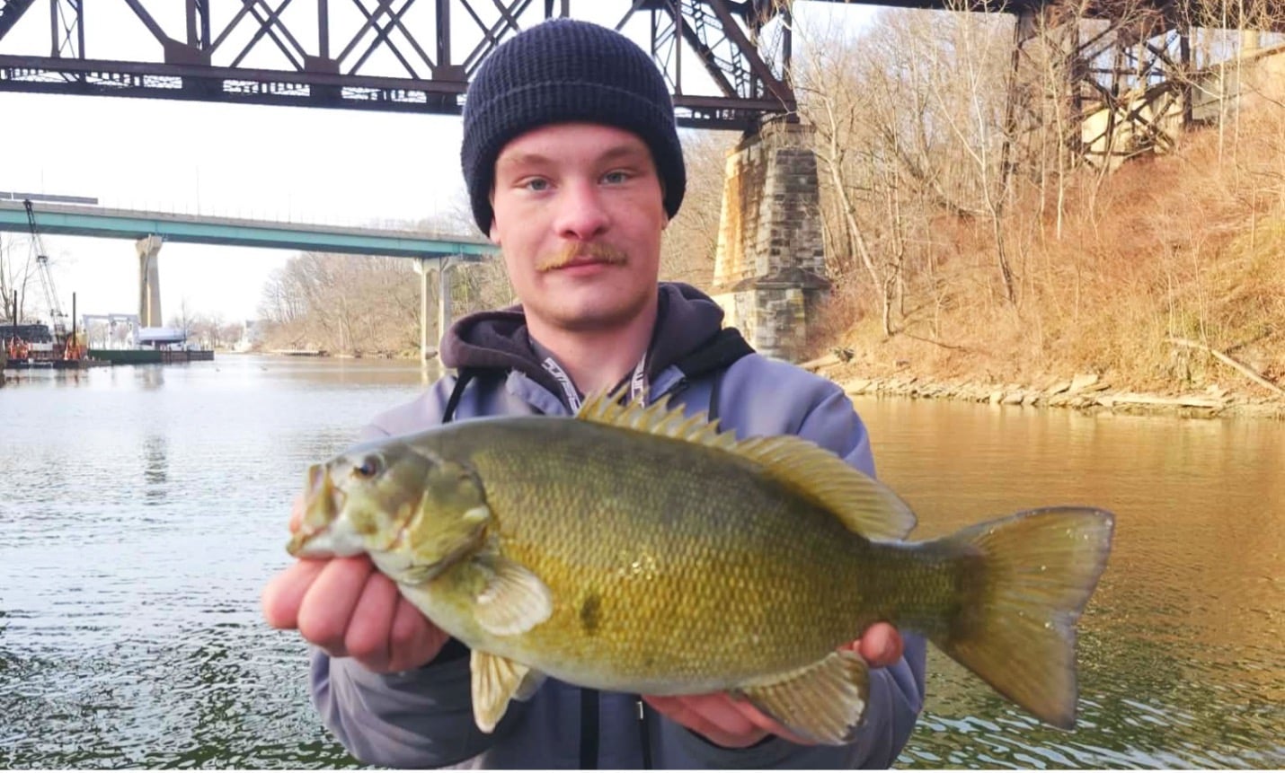 Man holding a smallmouth bass by the Rocky River marina