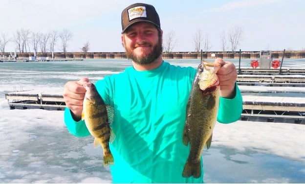 Photo of man holding two fish on fishing pier