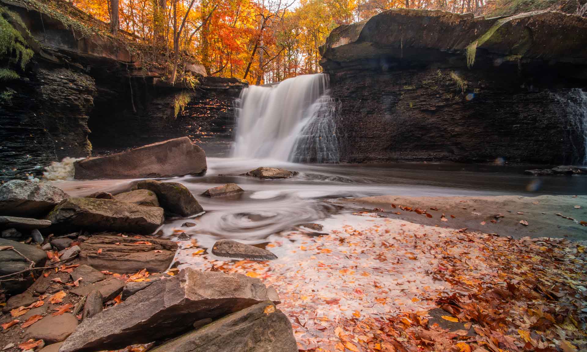 A waterfall over a rock ledge into a pond