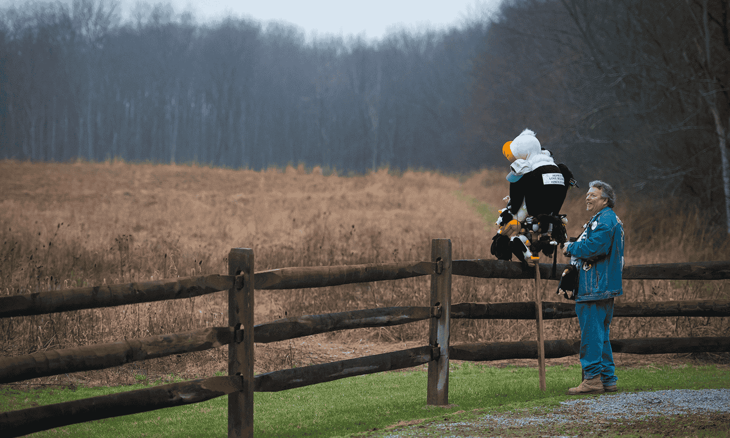 Man standing at a fence with a stuffed buzzard