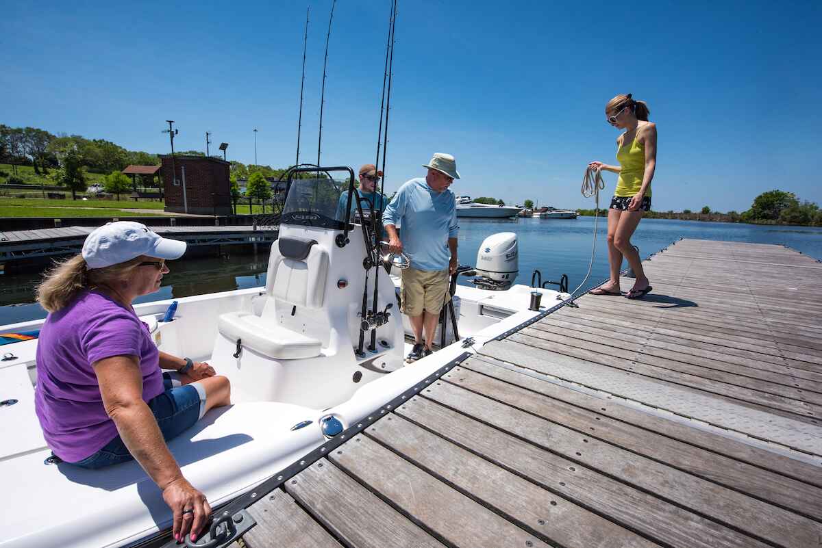 A family gathered on a boat at the dock, enjoying a sunny day together, with smiles and laughter all around.