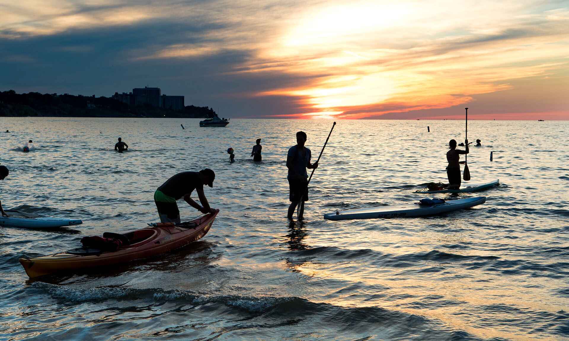 People kayaking on water at sunset