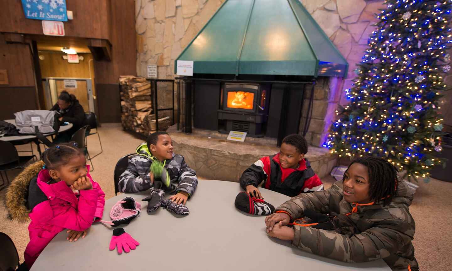 Group of kids sitting at a table in front of a fireplace