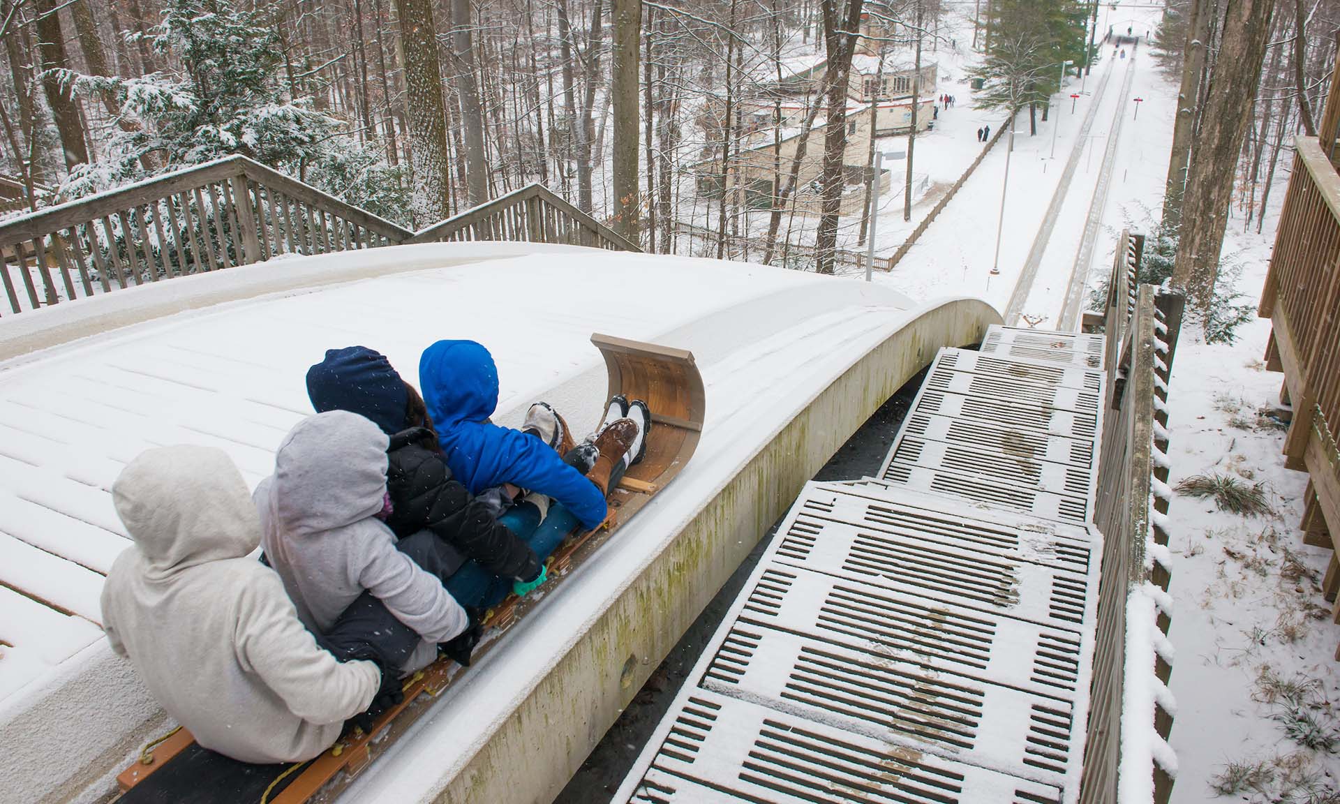 Children sledding down a wooden ramp