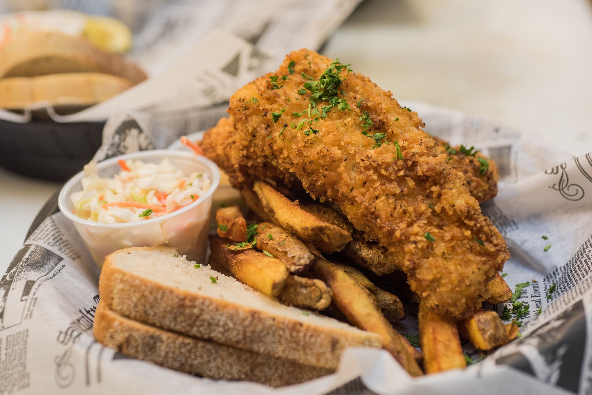 A delicious fried fish dinner with fries, cole slaw, and bread. 