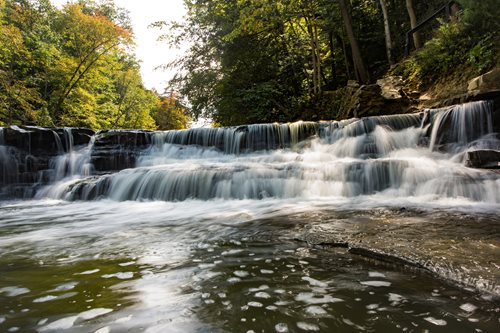 arafed waterfall in the woods with water flowing over it, a jigsaw puzzle by Mike Bierek, instagram contest winner, hudson river school, cascading waterfalls, waterfalls and lakes, water cascading