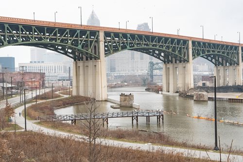 there is a bridge that is over a river with a boat going under it, a photo by Joe Stefanelli, instagram contest winner, ecological art, cleveland, high bridges, soaring towers and bridges