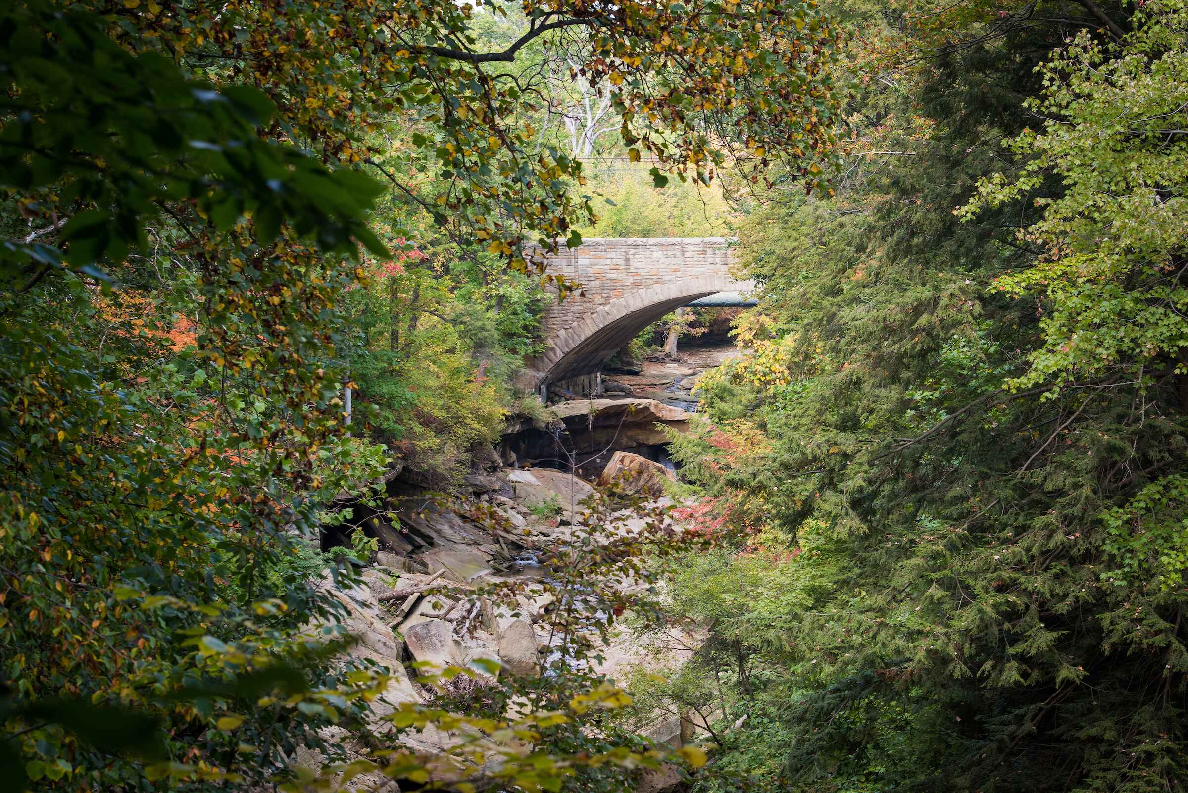 there is a bridge over a stream in the woods, a tilt shift photo inspired by Asher Brown Durand, shutterstock contest winner, hudson river school, old stone bridge over the creek, stone bridge over brook, stone bridge